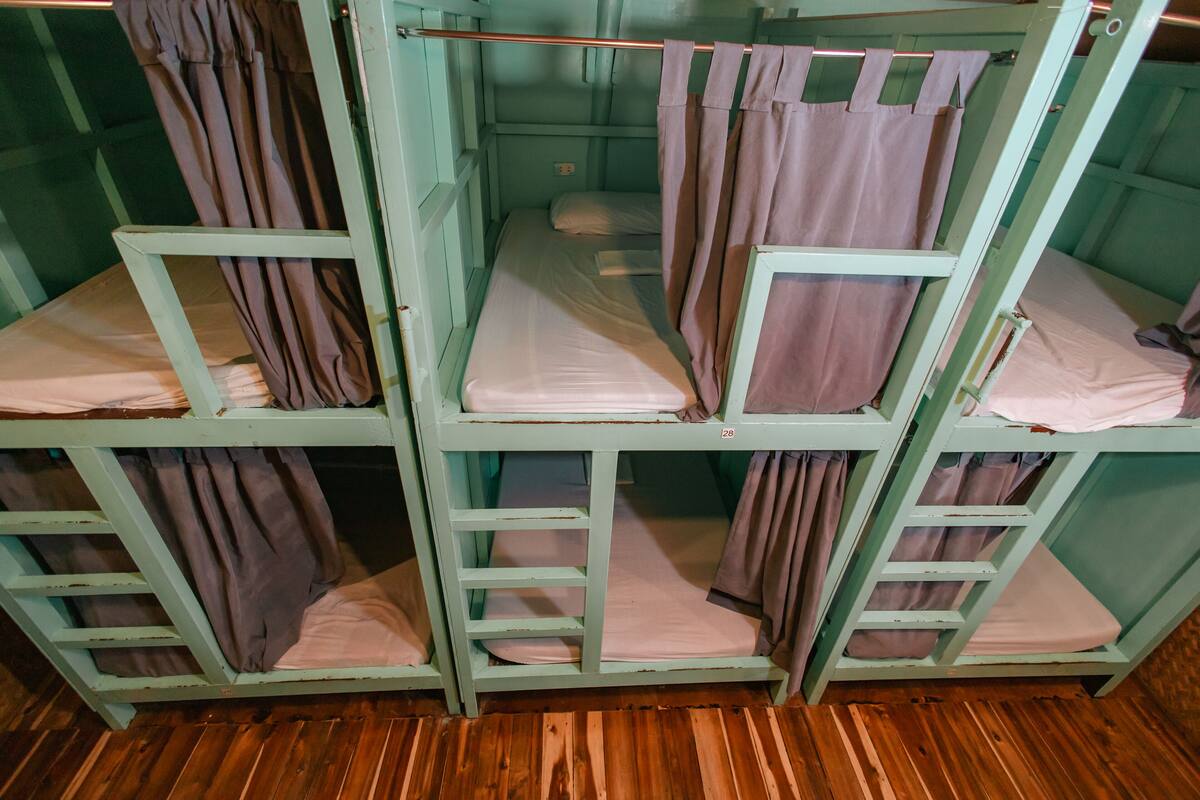Bunk beds with curtains, wooden flooring, and a green wall.