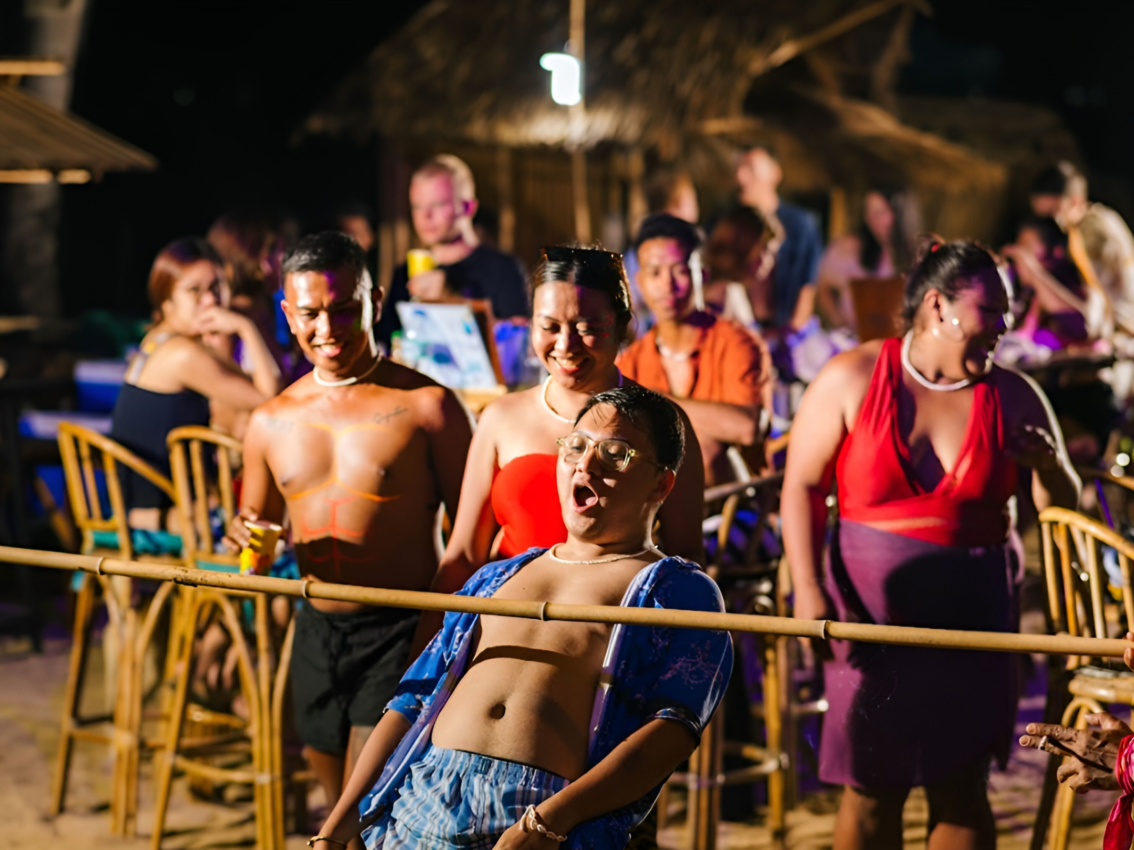 A crowded outdoor event with people standing and sitting around tables.