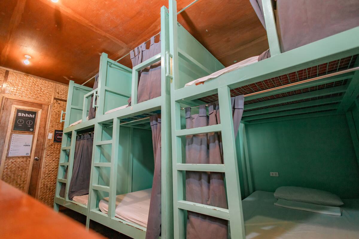 A bunk bed room with a wooden ceiling and a sign on the wall.
