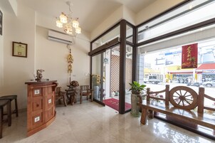 Zona de recepción con mostrador de madera, sillas, un adorno colgante y vista a la calle.