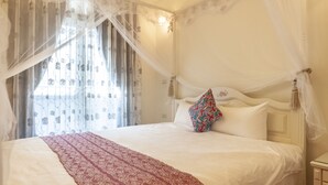 Ein Bett mit Baldachin, weißer Bettwäsche und einer gemusterten Decke.
