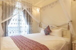Una cama con dosel, ropa de cama blanca y un edredón estampado.