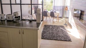 A modern kitchen with a dining area, a TV mounted on the wall, and a balcony with a view.