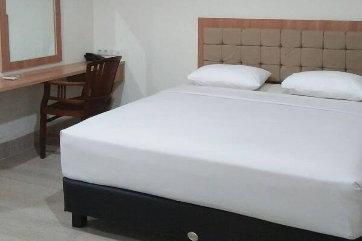A hotel room with a bed, a desk, and a chair.