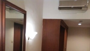 Um quarto com uma escrivaninha de madeira, um espelho, uma luminária na parede e piso ladrilhado.