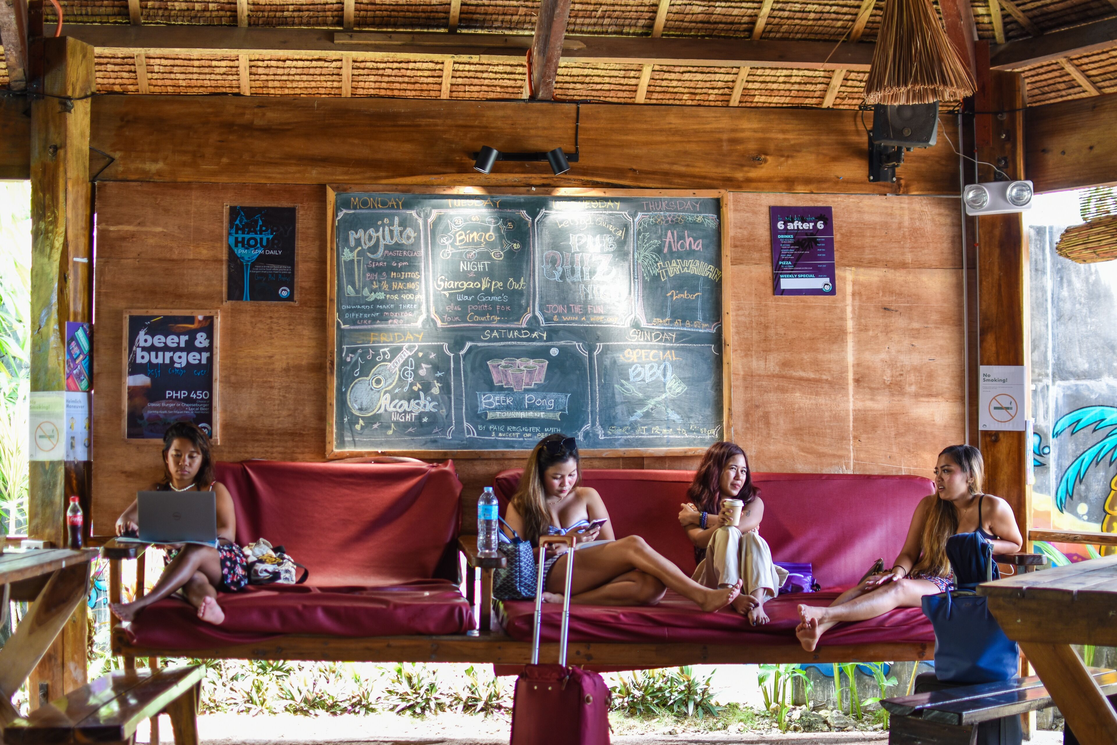A wooden interior with a red couch and a chalkboard menu listing events.