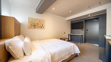 Un dormitorio moderno con una cama grande, un cabecero de madera, una mesita de noche pequeña, un escritorio y una puerta que da a un baño.
