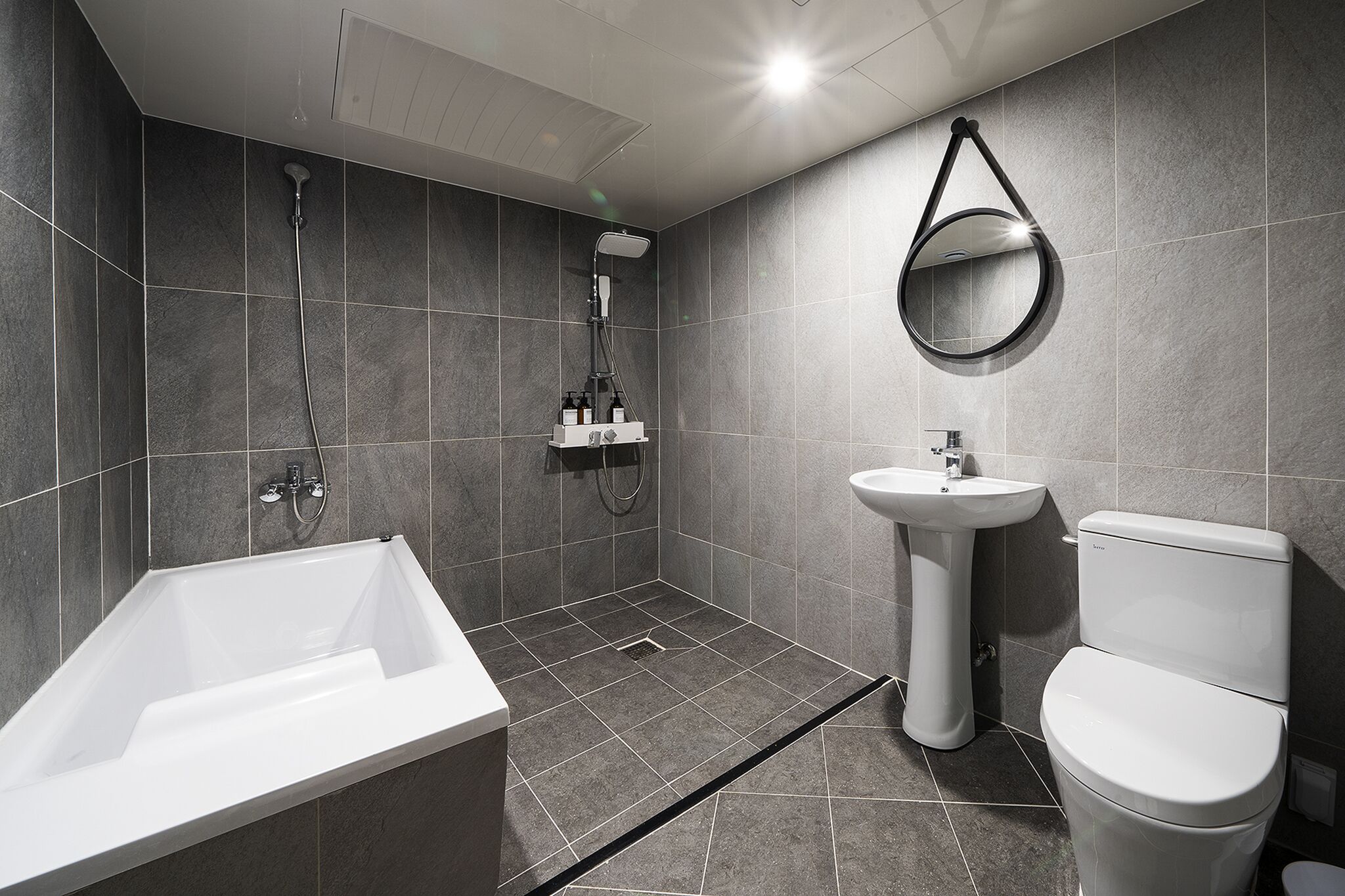 A modern bathroom with a bathtub, shower, sink, and toilet.