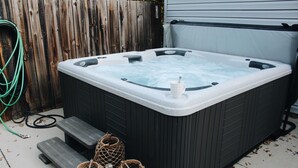 Un jacuzzi con una terraza de madera y escalones que llevan a él.