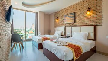 A hotel room with two beds, a brick wall, a city view, and a large window.