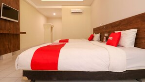 Une chambre d’hôtel moderne dotée d’un grand lit, d’un téléviseur à écran plat fixé au mur et d’un appareil de climatisation.