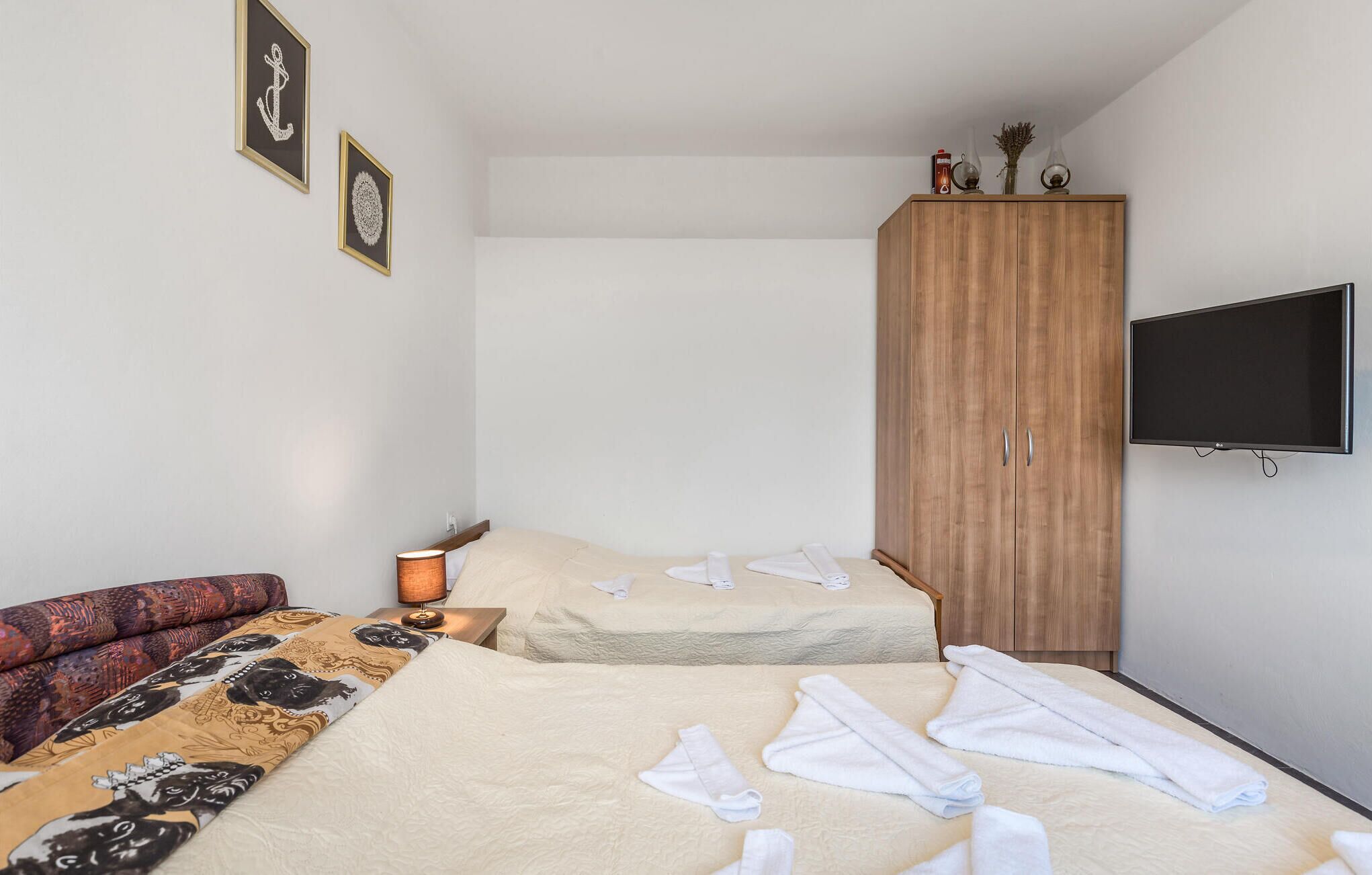 Une chambre d’hôtel avec deux lits, une armoire, une télévision et une lampe.