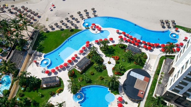 An aerial view of a resort with multiple swimming pools, sun loungers, and umbrellas. - View and Breeze  w/cleaning service (Las Glorias)