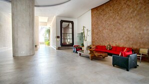 A spacious lobby with a red sofa, a wooden coffee table, and a large pillar. - View and Breeze  w/cleaning service (Las Glorias)