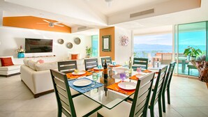 A modern living room with a dining area, large windows, and a ceiling fan. - View and Breeze  w/cleaning service (Las Glorias)