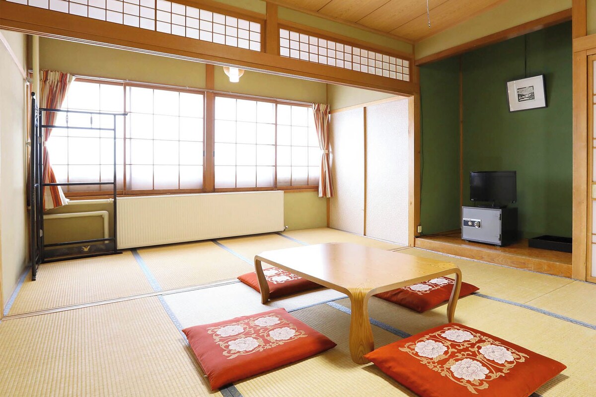 Une pièce de style japonais traditionnel, avec un sol recouvert de tatamis, une petite table en bois et des coussins.