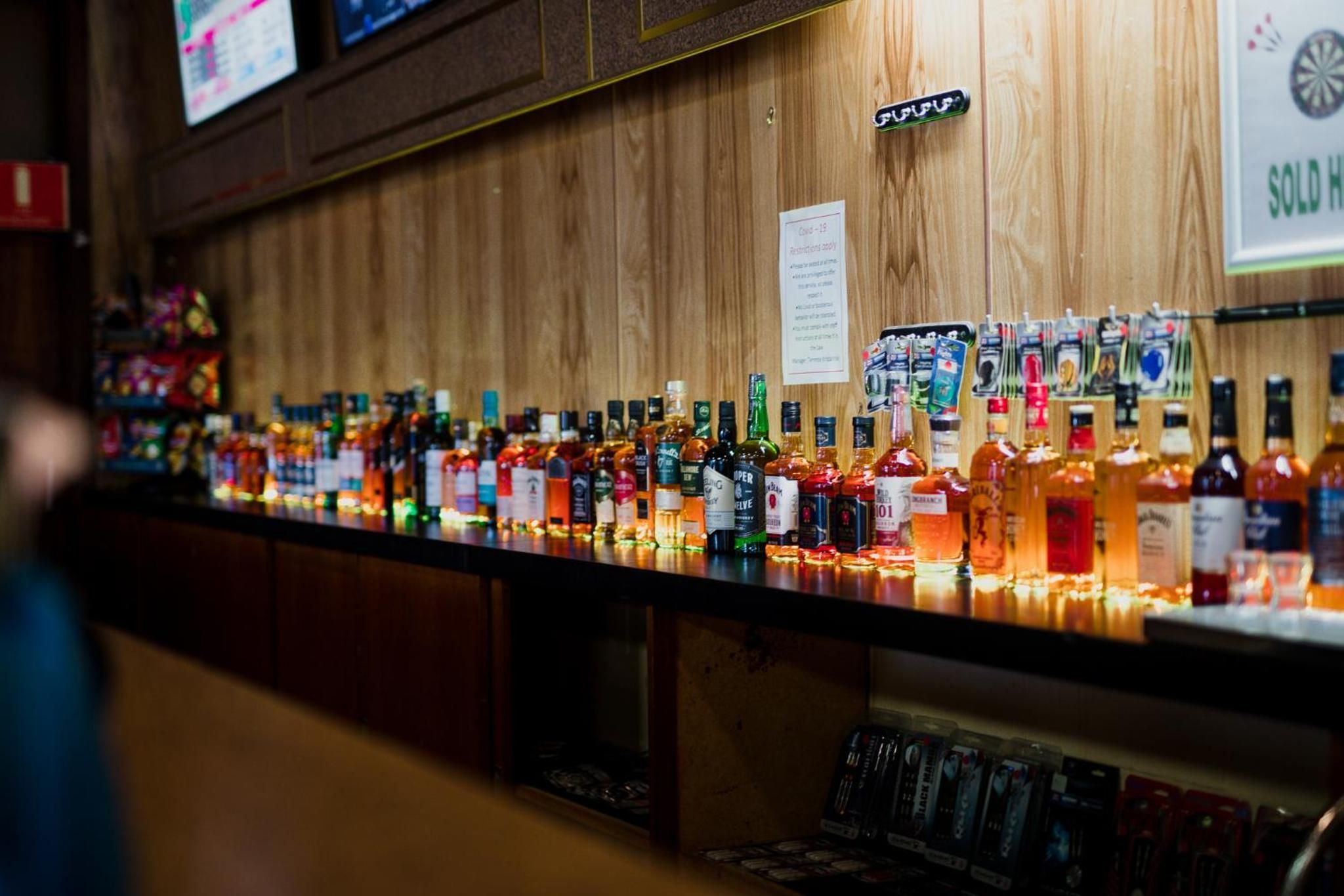 A bar with a variety of liquor bottles and a sign indicating a sold house.