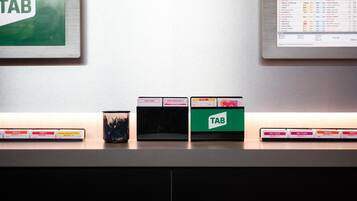 Una mesa con una caja verde etiquetada 'TAB' y varias cajas más con etiquetas como 'TRIFECTA' y 'PRIMEROS 4'.