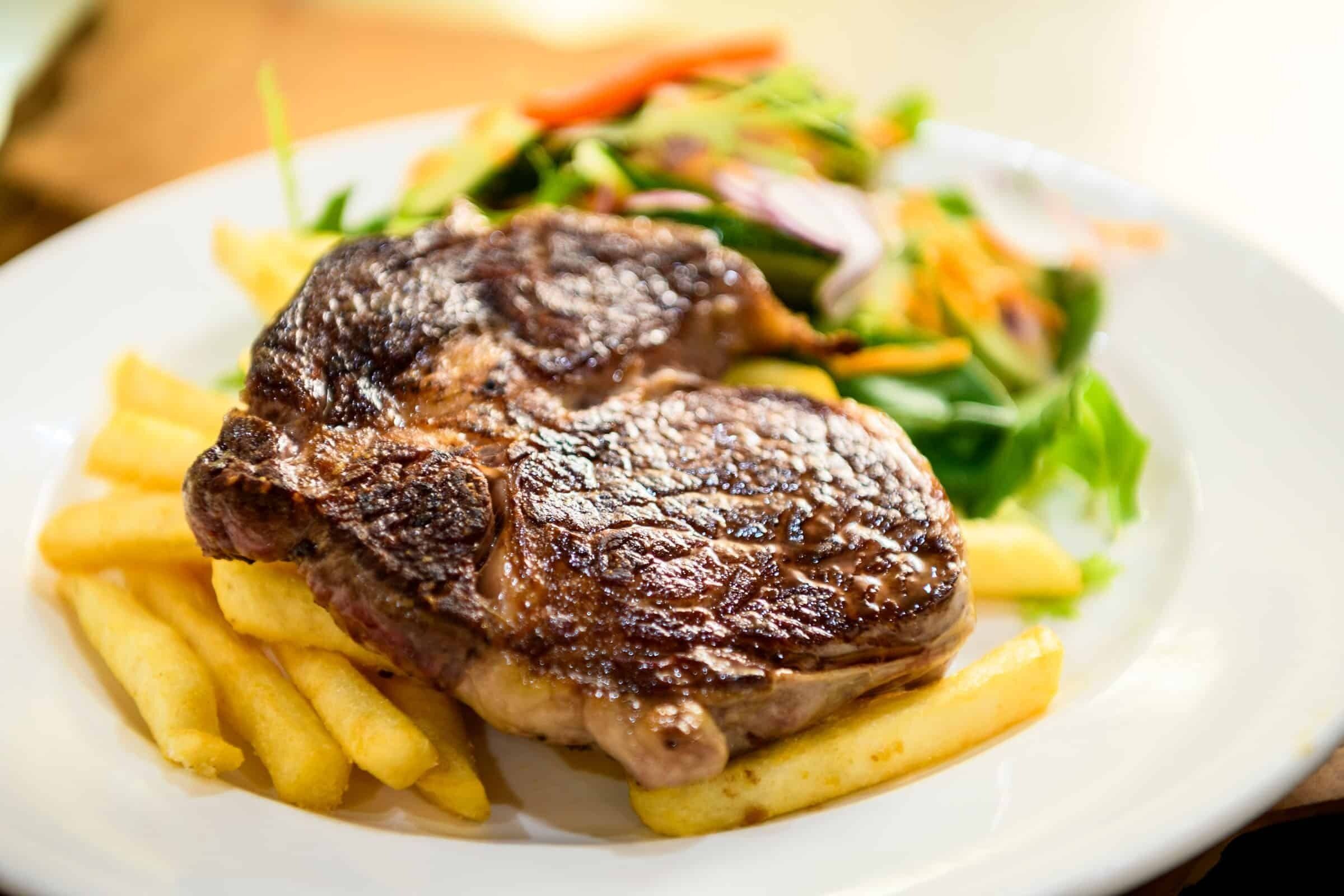 Una bistecca con patatine fritte e un'insalata su un piatto.