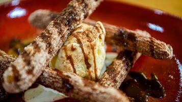 Un postre con churros, helado y salsa de chocolate en un plato.
