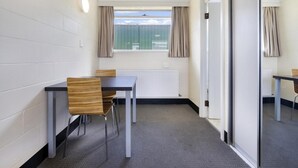 A room with a table and chairs, a radiator, a window with curtains, and a sliding door. - Top of the Town Hotel Motel (Upper Burnie)