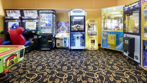 Une rangée de bornes d’arcade dans une pièce dont le sol est recouvert d’un tapis à motifs.