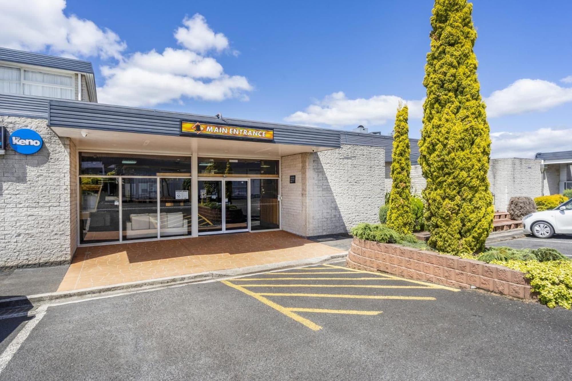 Un bâtiment avec une enseigne indiquant « ENTRÉE PRINCIPALE » et une zone de stationnement délimitée par des lignes jaunes.
