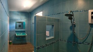 Un baño con azulejos azules, un lavabo, un espejo y una ducha.