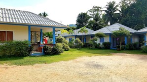 Une rangée de bâtiments d’un seul étage, aux façades bleues et blanches, entourés de pelouses bien entretenues et d’une végétation tropicale.