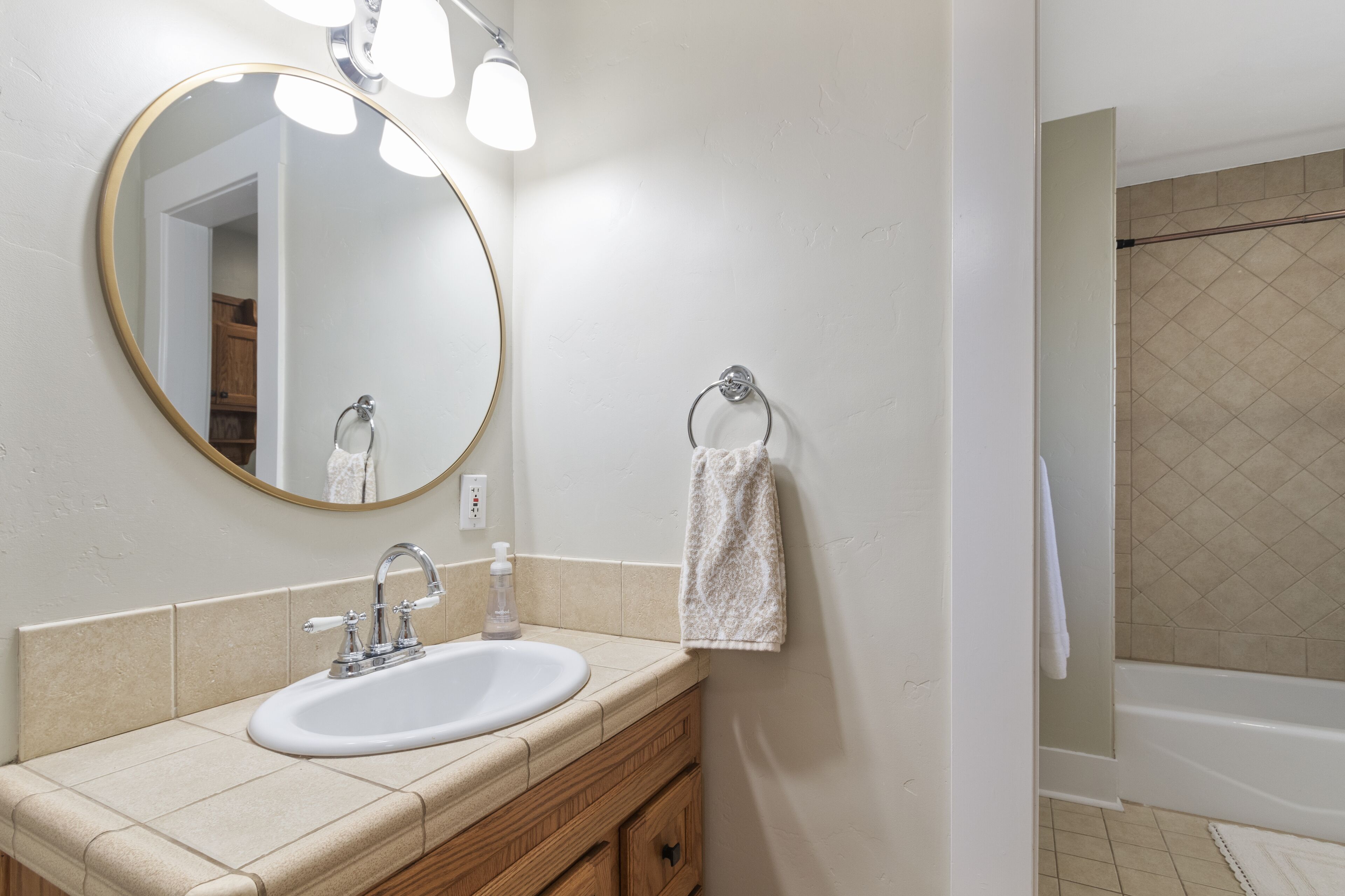 Un bagno con lavandino, specchio e portasciugamani.