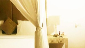 A hotel room with a bed, a nightstand, a lamp, and a curtain. - Palm Hill Guest House (Talalla)