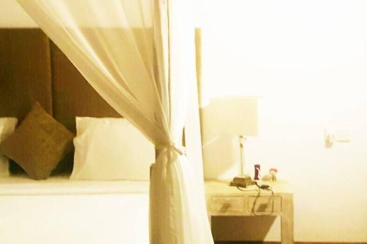 A hotel room with a bed, a nightstand, a lamp, and a curtain.
