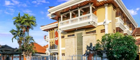 Un edificio tradicional con balcón, portón y una palmera.