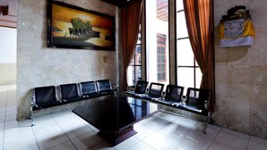 Une salle de conférence avec une grande table et six chaises, un tableau au mur et une fenêtre avec des rideaux.