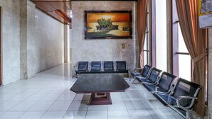 Une salle de conférence avec une grande table et plusieurs chaises, une fresque murale et de grandes fenêtres avec des rideaux.