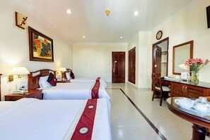 A hotel room with two beds, a desk with a mirror, a clock, and a painting on the wall. - Hung Phong Hotel (Xuan Huong - Da Lat)