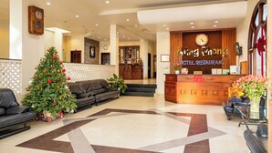 A hotel lobby with a reception desk, Christmas trees, and leather sofas. - Hung Phong Hotel (Xuan Huong - Da Lat)