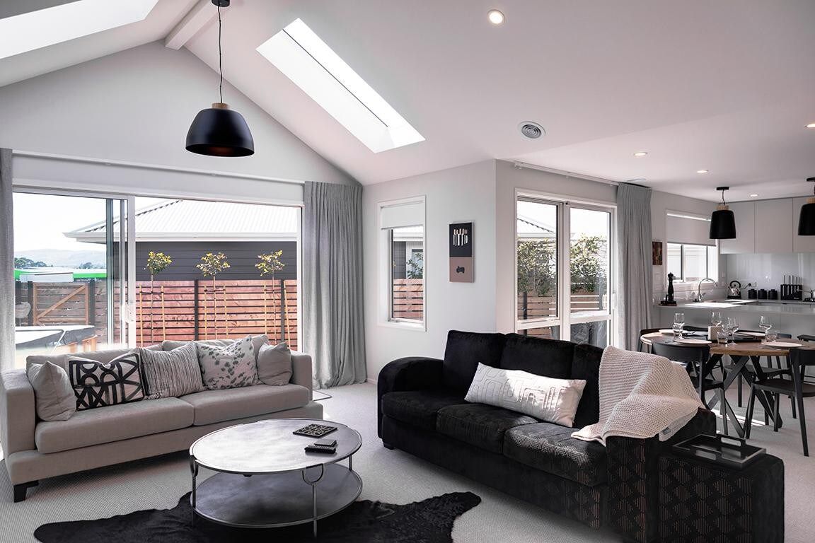 A modern living room with a sofa, coffee table, and dining area. - The Gallery - Central, Spa Pool, Sleeps 6 (Rotorua)