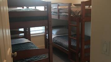 A room with bunk beds, a door, a window, and a light switch.