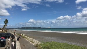 A beach with a paved walkway, parked cars, and a few people. - Guest House & Bar Diamond Head (Mihama)