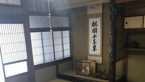 A traditional Japanese room with tatami flooring, a wooden table with a box and a remote control, a shoji screen, and a calligraphy scroll. - Guest House & Bar Diamond Head (Mihama)