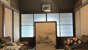 A traditional Japanese room with tatami flooring, a low table, two sofas, and shoji screens. - Guest House & Bar Diamond Head (Mihama)