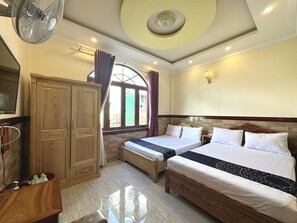 Habitación de hotel con dos camas, un armario, un tocador y un ventanal con cortinas.