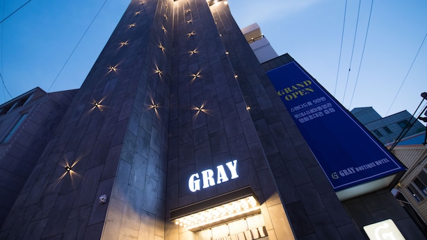 A tall building with a prominent 'GRAY' sign and a 'Grand Open' banner. - Gray Hotel (Tongyeong)