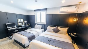 A modern hotel room with two beds, a desk with a computer, a mirror, and an air conditioning unit. - Gray Hotel (Tongyeong)