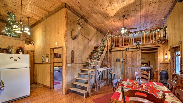A rustic wooden interior with a dining area, staircase, and a kitchen with a refrigerator. - 'The Bovard Lodge' Rustic Cabin Near Ohio River! (Florence)
