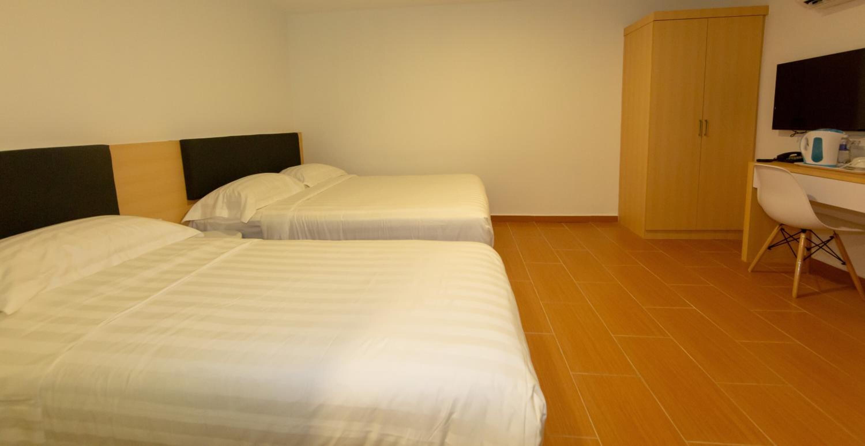 Une chambre d’hôtel avec deux lits, un bureau, une chaise et un téléviseur.