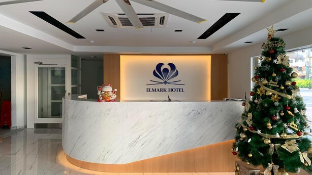 Een hotel receptie met een marmeren balie, een plafondventilator en een kerstboom.