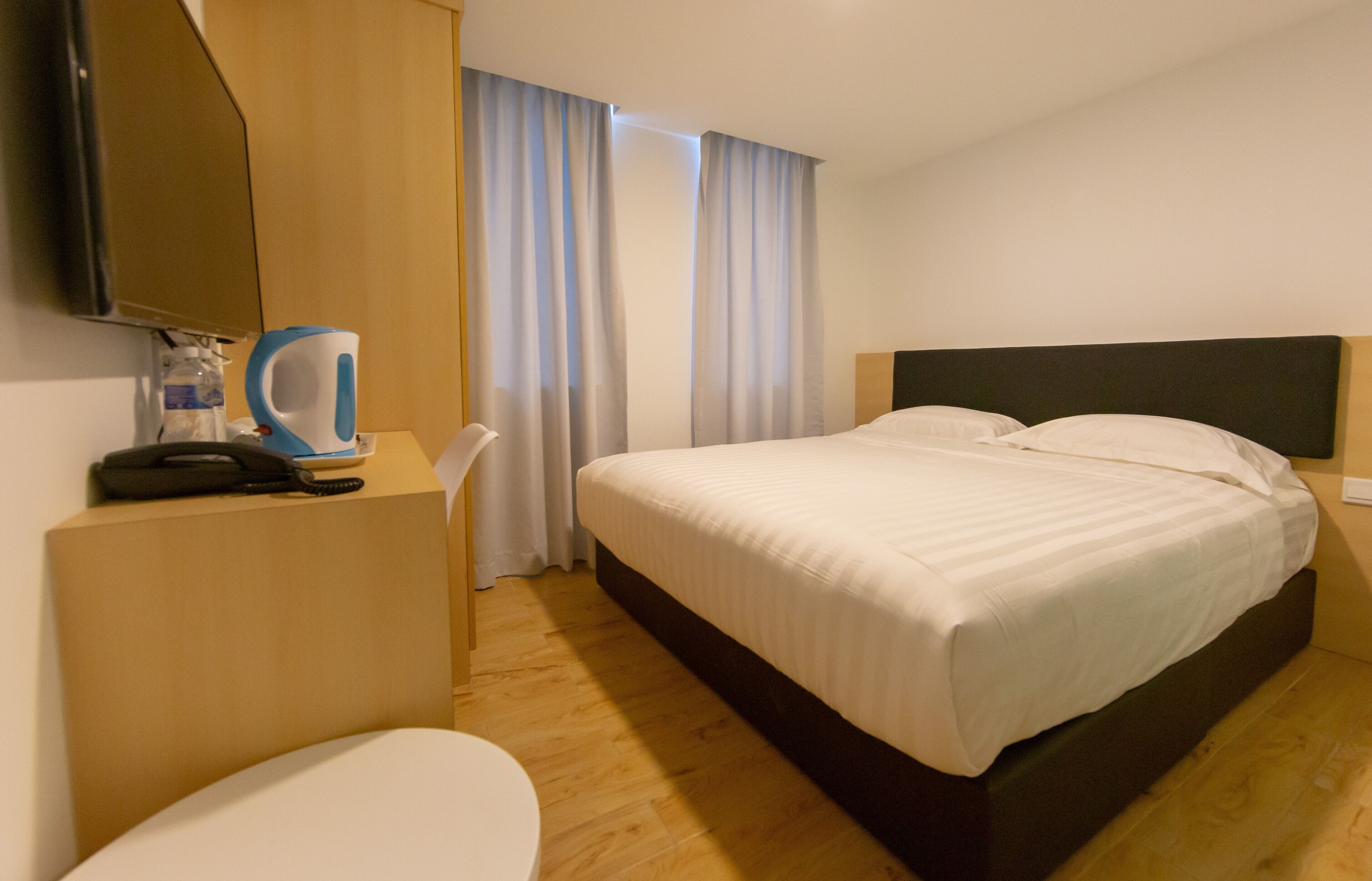 A hotel room with a bed, a desk, a chair, a television, and a coffee maker.
