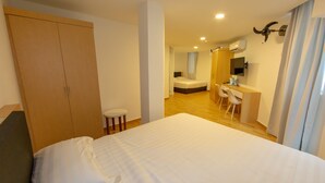 Hotelkamer met een groot bed, een bureau met stoelen, een kledingkast en een badkamer die door een open deur zichtbaar is.